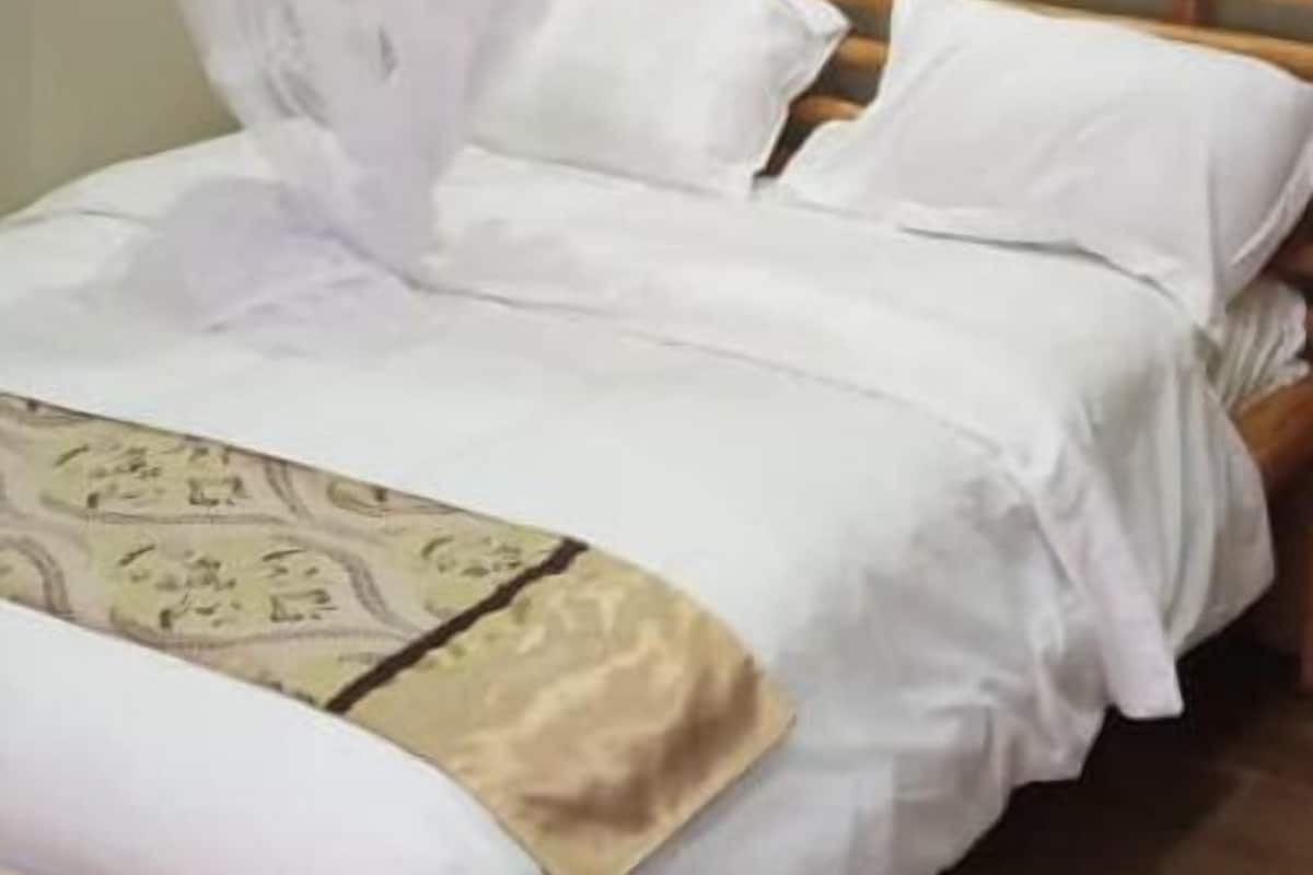 Un lit à baldaquin, avec une tête de lit en bois et une couvre-lit à motifs.