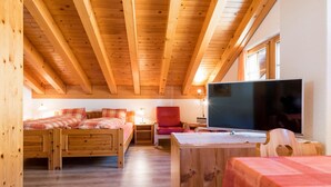 A cozy cabin with a loft bedroom, a TV, and a dining area.