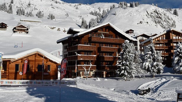 A snow-covered mountain resort with wooden buildings and ski slopes.