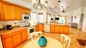 A spacious kitchen with wooden cabinets, a central island, and a dining area with a table and chairs.