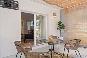 An outdoor patio with wicker furniture, a glass table, and a potted plant. - Oasis Heated Pool Spa Fenced Yard Bicycles (Palm Coast)