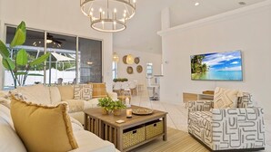Una sala moderna con sofá, sillón estampado y una mesa de centro con objetos decorativos.