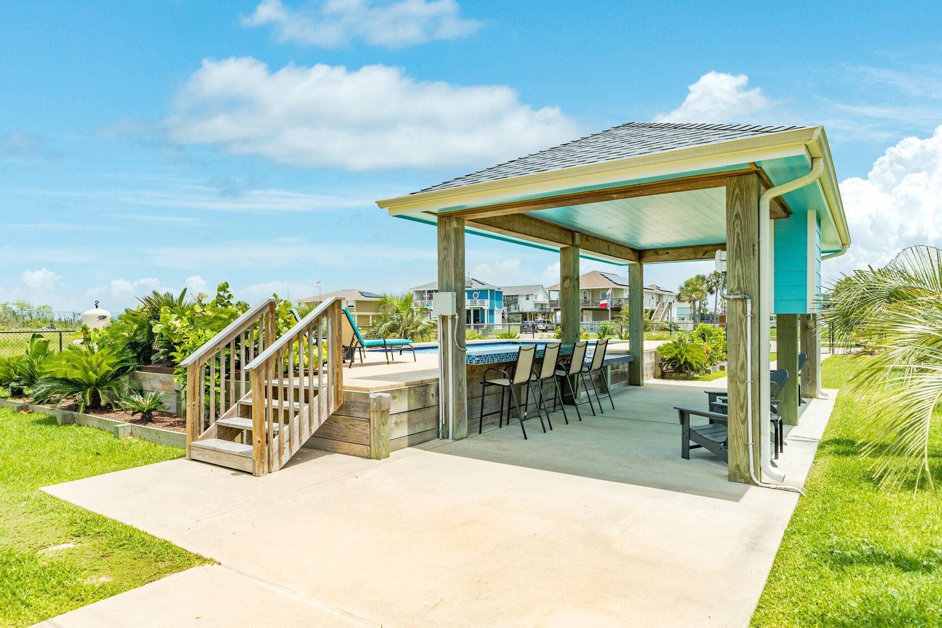 Un espacio al aire libre techado con piscina, terraza de madera y mobiliario.