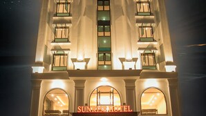 Un hôtel dont l’enseigne, bien visible, porte l’inscription « SUNRISE HOTEL » en haut.
