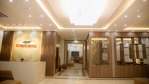 Un espace d’accueil comprenant un comptoir de réception, un lustre et une enseigne indiquant « Sunrise Hotel ».