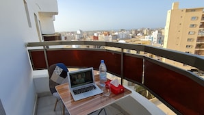 En balkon med en bærbar computer, en vandflaske og en kasse med servietter.