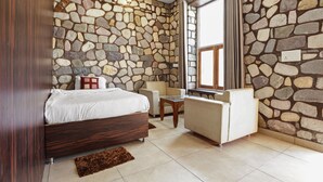 A bedroom with a stone wall, a bed, a small table, and a chair. - 1B-Wild Heritage-101 N By bnbmehomes (Salt)