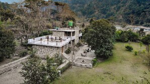 A stone building with a balcony, surrounded by trees and a river. - 1B-Wild Heritage-101 N By bnbmehomes (Salt)