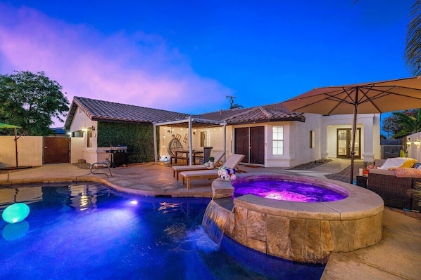 A backyard with a swimming pool, a hot tub, and outdoor furniture.