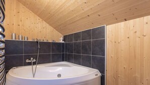 A modern bathroom with a freestanding bathtub, dark tiles, and wooden paneling. - Superior #43 mit Sprudelwanne by Interhome (Hohentauern)