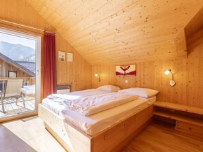 Ein Schlafzimmer in einer Holzhütte mit einem Bett, einer Bank und Blick ins Freie.