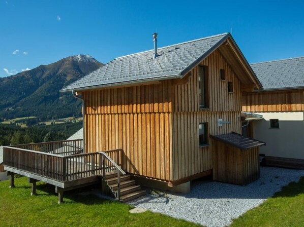 Eine Holzhütte mit geneigtem Dach, einer Holterrasse und einer Treppe zum Eingang.