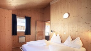 A wooden room with a bed, a window with curtains, a wall-mounted light, and a door. - Premium #14 mit IR-Sauna by Interhome (Hohentauern)