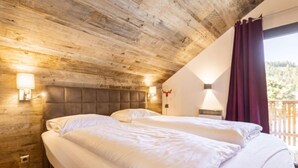 Ein Schlafzimmer mit Holzboden, zwei Betten, einem Nachttisch und Blick ins Freie.