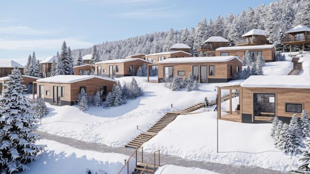 A modern resort with wooden cabins, a central walkway, and a snowy forest backdrop.