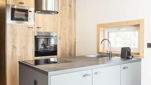 A modern kitchen with wooden cabinetry, stainless steel appliances, a window, and a built-in sink.