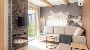 A modern living room with a stone fireplace, a sofa, a coffee table, and a large window with curtains.