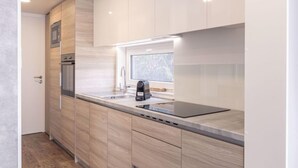A modern kitchen with wooden cabinets, a built-in oven, and a window above the sink. - mit 2 Schlafzimmern by Interhome (Kötschach-Mauthen)