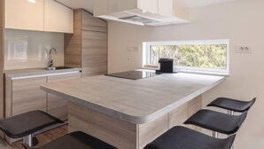 Una cocina moderna con una isla central, taburetes de bar y un ventanal con vistas al exterior.
