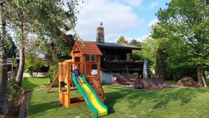 A wooden playhouse with a slide and a chimney. - BIBERCHALET and BIBERBAU as compl. House with terrace, garden and garden sauna (Bad Lauterberg im Harz)