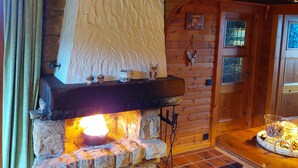 A stone fireplace with a white textured mantle, wooden walls, and a tiled floor. - BIBERCHALET and BIBERBAU as compl. House with terrace, garden and garden sauna (Bad Lauterberg im Harz)