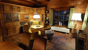 A cozy log cabin interior with a wooden dining table, chairs, a sofa, and a fireplace. - BIBERCHALET and BIBERBAU as compl. House with terrace, garden and garden sauna (Bad Lauterberg im Harz)