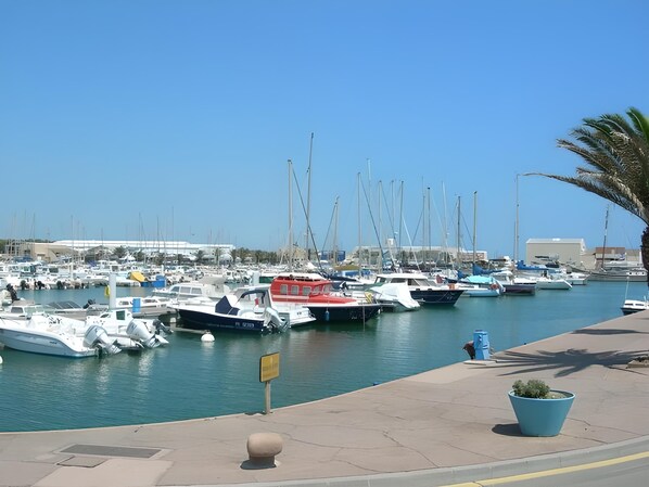 A marina with various boats docked, a clear sky, and a few buildings in the background. - LARGE TERRACE FACING THE SEA Canet-Sud,2/4 PERSONS, PARKING, AIR CON.,WIFI (Canet-en-Roussillon)