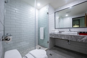 A modern bathroom with a glass shower enclosure, a white toilet, a sink with a marble countertop, and a large mirror above the sink. - Howard RESORT Xitou (Lugu)
