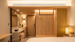 Un dormitorio moderno con una cama grande, un armario de madera, un tocador con espejo y una mesita de noche.