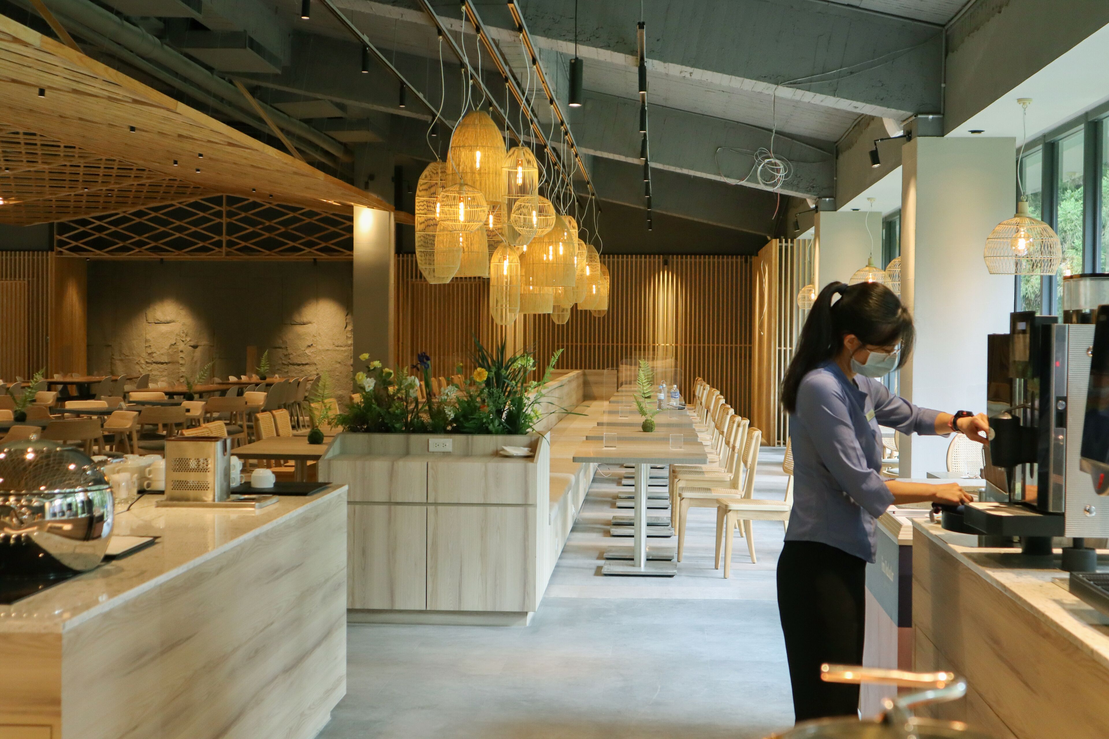 En moderne restaurant med en lang disk, træloft, hængende lamper og et barområde.
