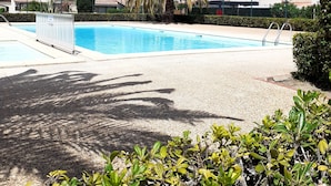 A swimming pool surrounded by palm trees and a clear blue sky.