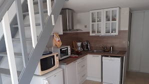 A compact kitchen with white cabinets, a microwave, a coffee maker, and a dishwasher.