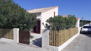 A residential property with a tiled roof, a wooden fence, and a parked white car.