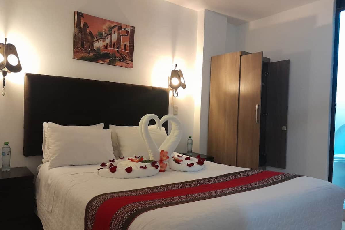Habitación de hotel con una cama, cabecero, un cuadro en la pared y un armario.