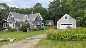 A house with a gravel driveway, a front yard with flowers, and a garage.