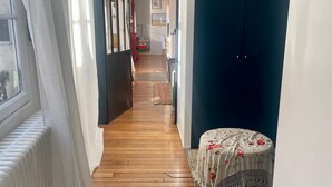 Un pasillo estrecho con suelo de madera, un radiador y una mesa con mantel floral.