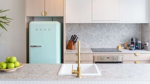Una cucina moderna con un frigorifero azzurro chiaro, un piano cottura integrato e un ripiano accessoriato con utensili da cucina.
