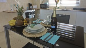 A dining table set with plates, a bottle of wine, and a pineapple. - Cap Confort (Mahé Island)