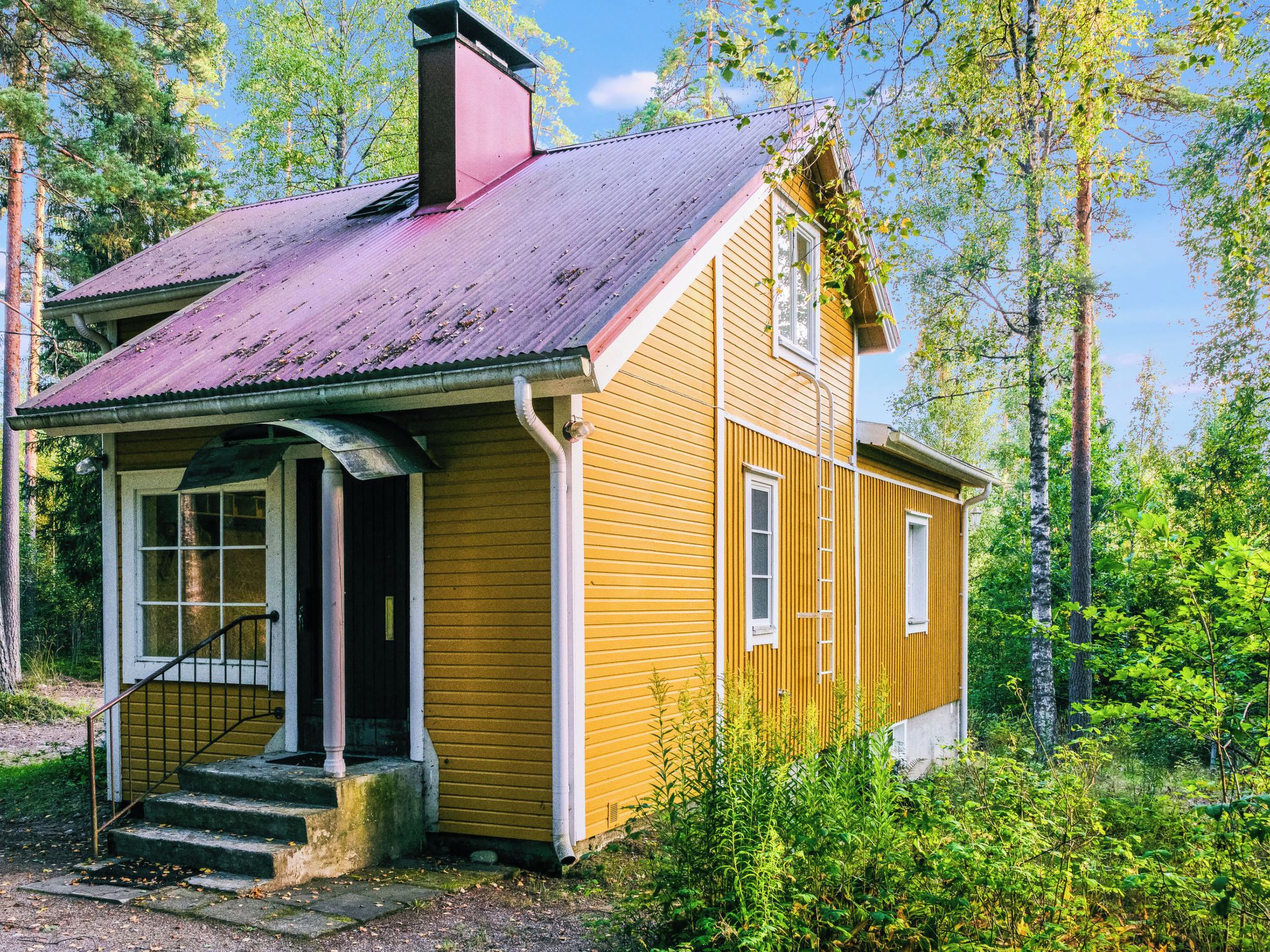 A small, single-story wooden house with a porch, a chimney, and a window.