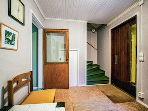 A hallway with a wooden door, a staircase, and a bench.