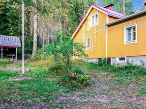 A yellow house with a red roof, surrounded by trees and a small garden. - Hiljanrinne by Interhome (Hausjärvi)