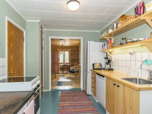 Une cuisine dotée d’un plan de travail en bois, d’un lave-vaisselle encastré et d’un luminaire suspendu.