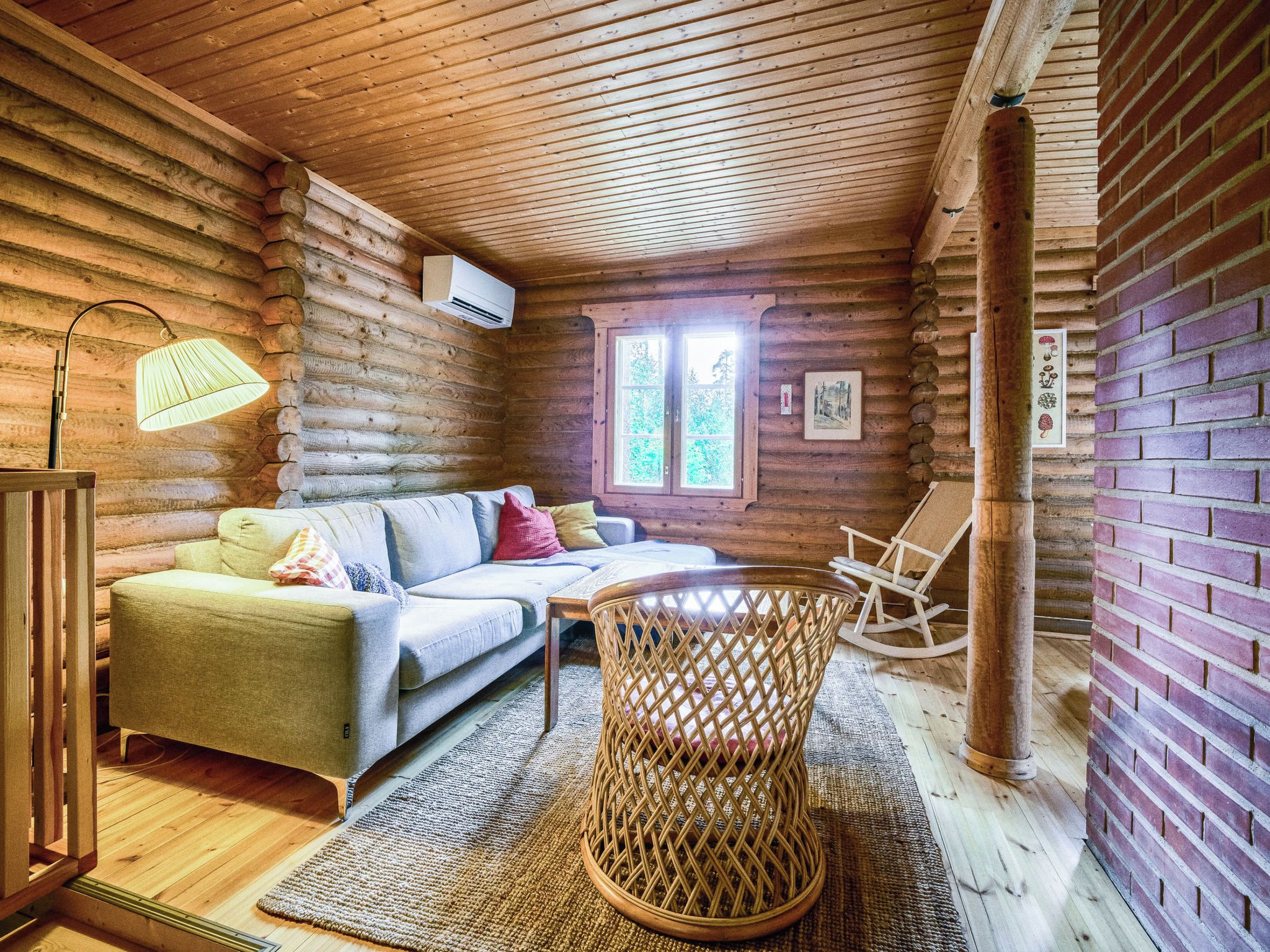 L’intérieur d’un chalet confortable, avec un canapé, un fauteuil en osier et une petite table.