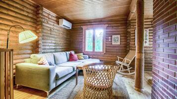 L’intérieur d’un chalet confortable, avec un canapé, un fauteuil en osier et une petite table.