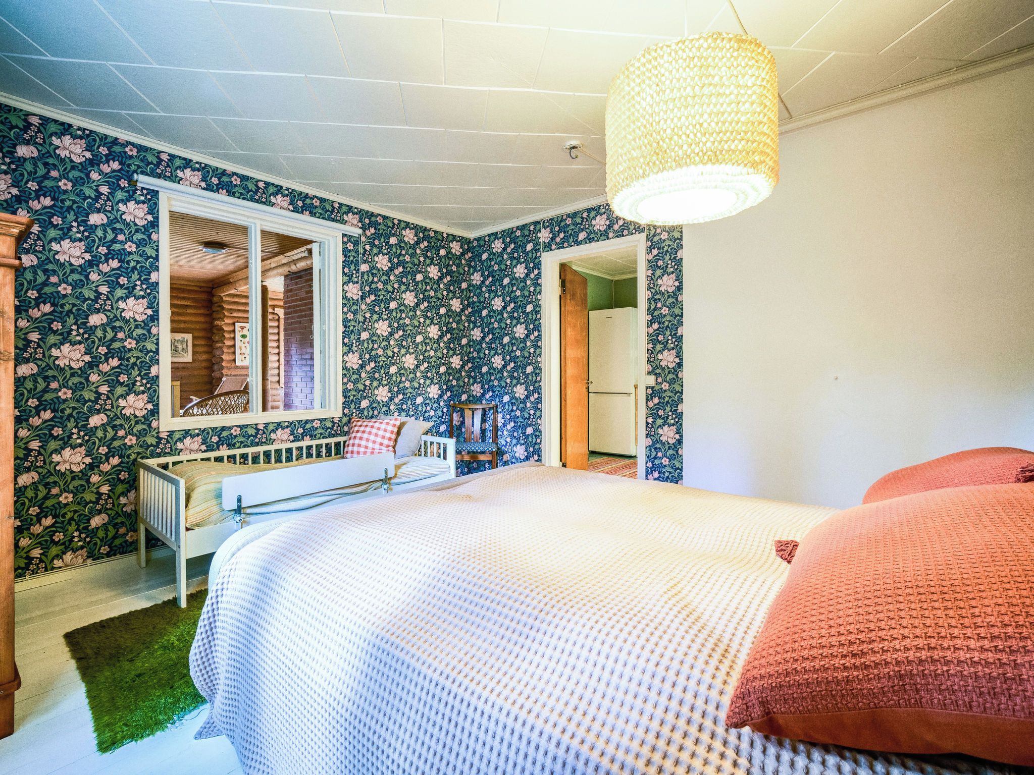A bedroom with a bed, a dresser, a mirror, and a door leading to another room.