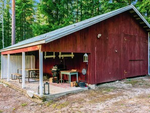 A rustic wooden barn with a covered porch, a table, chairs, a grill, and a lantern. - Hiljanrinne by Interhome (Hausjärvi)
