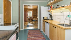 Eine Küche mit Holzausstattung, einem weißen Kühlschrank und einer gefliesten Spritzschutzwand.