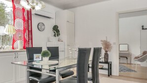A modern dining area with a glass table, black chairs, and a red patterned curtain.