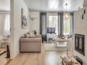 Uma sala de estar moderna com sofá, televisão, lareira e área de jantar.