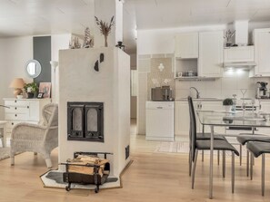 A modern kitchen with white cabinetry, a dining area with a glass table, and a fireplace with a decorative mantel.